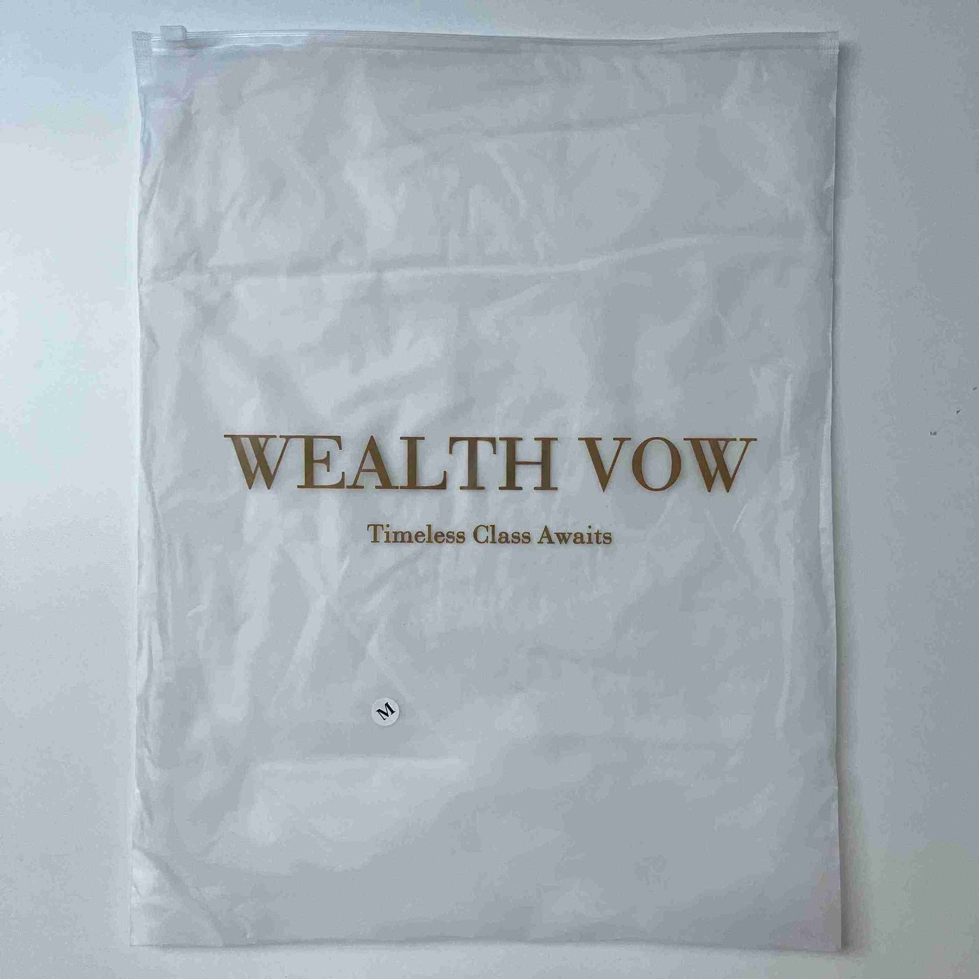 White garment bag with 'WEALTH VOW' text on a light gray background