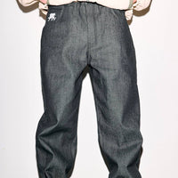 Person wearing dark gray pants and brown boots against a plain background